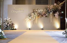 an aisle decorated with flowers and greenery for a wedding or special event in front of a white wall