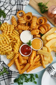 a white plate topped with french fries and onion rings next to ketchup sauce