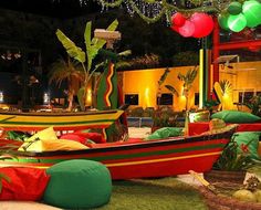 several colorful boats are on display at an outdoor event in the evening, with balloons and decorations hanging from the ceiling