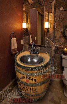 a bathroom with a sink, toilet and stone wall in it's own area