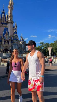 a man and woman standing in front of a castle