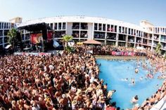 a large group of people are gathered around a pool in the middle of a city