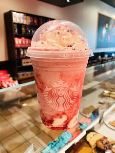 a starbucks drink with whipped cream and chocolate chip cookies on the counter in a bakery