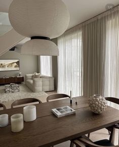 a dining room table with candles and vases on it in front of a large window