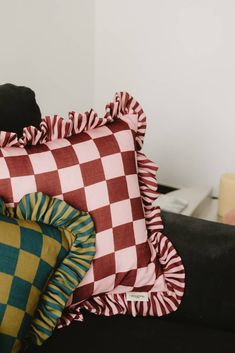 a black cat sitting on top of a couch next to some pillows and pillow cases