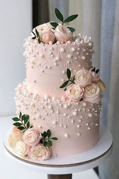 a pink wedding cake with white flowers and pearls