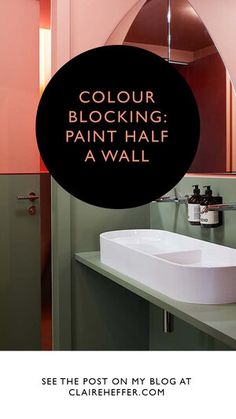 a bathroom with pink and green walls, white sink and black round sign that says color blocking paint half a wall