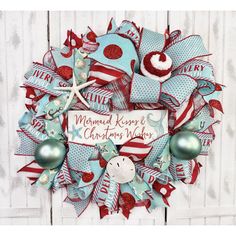 a christmas wreath with red, white and blue decorations hanging on a wooden wall next to a starfish ornament