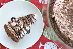 a piece of chocolate cake on a plate next to a dessert dish with whipped cream