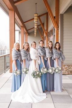 a group of women standing next to each other in front of a building with fur stoles