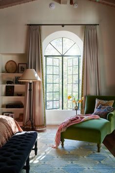 a bedroom with an arched window and green chair