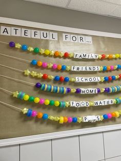 a bulletin board with colorful beads hanging from it's sides and words written on them