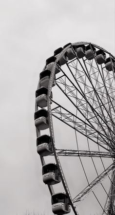 a ferris wheel in black and white against a gray sky with no one around it