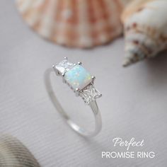 a white opal ring sitting on top of a table next to seashells