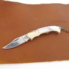 a knife that is sitting on top of a piece of brown leather with a chain around it