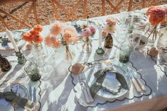 the table is set with flowers and place settings for an outdoor dinner or brunch