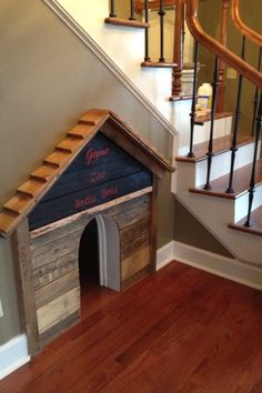 a dog house made out of pallets and wood with stairs leading up to the second floor