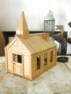 a small wooden house sitting on top of a table next to a lamp and other items