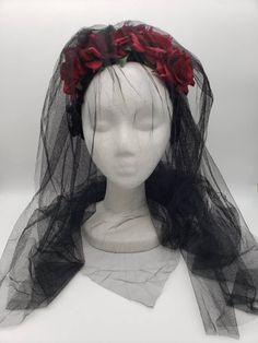 a white mannequin wearing a black veil with red roses on it's head