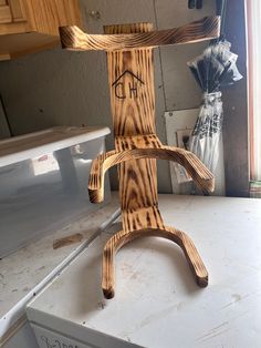 a wooden sculpture sitting on top of a dryer next to a window sill