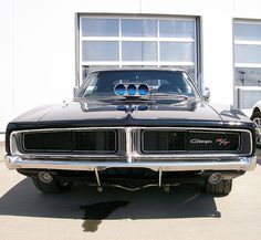 an old muscle car parked in front of a building