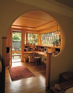 an arched doorway leads into a bedroom with a desk and computer on the other side