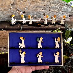 a person holding up a box with small figurines in the shape of angels