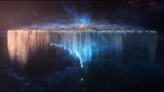 an island in the middle of water surrounded by ice and snow capped mountains with bright lights shining on it