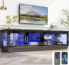 an entertainment center with blue lights and remotes in front of a television on the wall