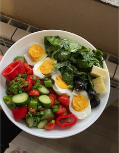 a white bowl filled with vegetables and hard boiled eggs