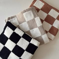 three different colored checkered towels sitting next to each other on a white table top