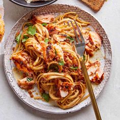 a plate of pasta with chicken and parmesan cheese on the side next to bread