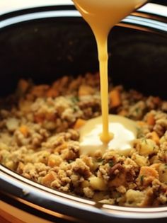 a crock pot filled with stuffing being poured into it