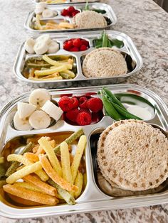 three trays filled with different types of food on top of a marble countertop