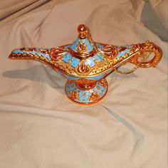 an ornately decorated blue and gold vase on a white cloth covered bed with sheets