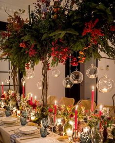 the table is set with candles, plates and vases filled with flowers on it