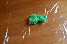 a piece of green tissue paper sitting on top of a wooden table next to a plastic bag