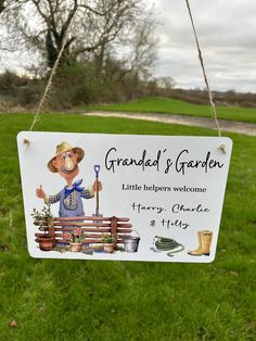 a sign hanging from the side of a grass covered field that says grandad's garden