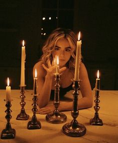 a woman sitting in front of candles with her hands on the table and looking at the camera