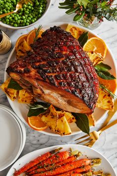 a large piece of meat sitting on top of a white plate next to carrots and asparagus