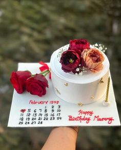 a hand holding a birthday cake with flowers on it