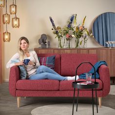 a woman sitting on a red couch holding a cup