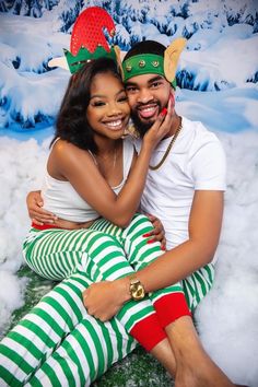 a man and woman are sitting in the snow with christmas decorations on their heads together