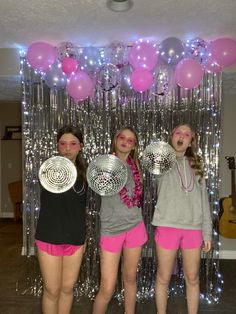 three girls standing in front of balloons and streamers