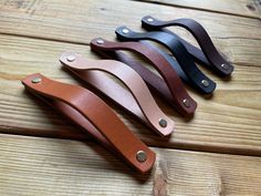 four different colored leather handles sitting on top of a wooden table