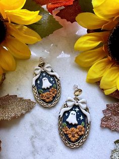 two halloween themed earrings sitting next to sunflowers