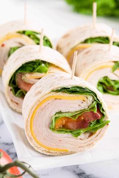 several sandwiches with toothpicks in them sitting on a white plate, ready to be eaten