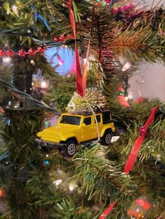 a christmas tree with a yellow car ornament hanging from it