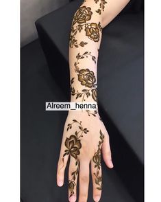 a woman's hand with henna tattoos on it and flowers painted on the arm