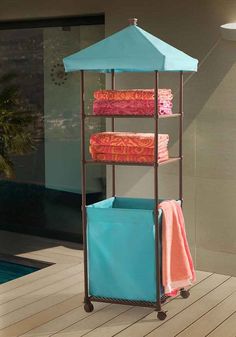 a rack with towels on top of it next to a swimming pool and an umbrella